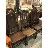 A pair of oak panel seated hall chairs together with another similar with coronet to top rail