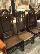 A pair of oak panel seated hall chairs together with another similar with coronet to top rail