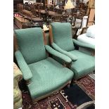A pair of Victorian open arm chairs with green self patterned upholstery and oak frames raised on