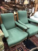 A pair of Victorian open arm chairs with green self patterned upholstery and oak frames raised on