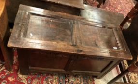 An 18th Century oak coffer the plain two panelled top over a lunette carved frieze and two plain