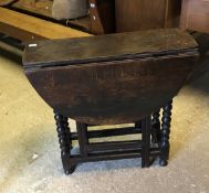 A 19th Century oak gate leg table on barley twist legs united by bobbin turned stretchers