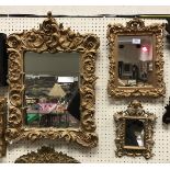 A small Rococo style carved giltwood framed wall mirror with scrolling acanthus decoration and two