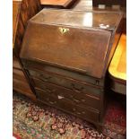 An 18th Century oak bureau of small proportions the plain top over a sloping fall enclosing a