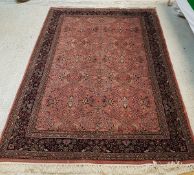 A Persian rug with all over floral decoration on a plum ground within a blue ground floral