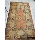 A Turkish terracotta and cream ground prayer rug with central lozenge shaped medallion within a