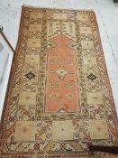 A Turkish terracotta and cream ground prayer rug with central lozenge shaped medallion within a