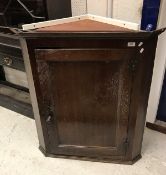 An 18th Century oak hanging corner cupboard the single panelled door enclosing a painted interior