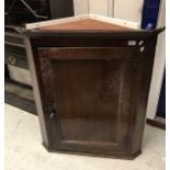 An 18th Century oak hanging corner cupboard the single panelled door enclosing a painted interior