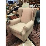 A modern Next upholstered wingback armchair raised on turned and ringed front legs