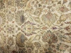 A Persian rug with all over exotic flower head design on a gold ground within a similarly decorated