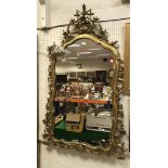 A gilt framed wall mirror with scrolling foliate decoration in the Rococo taste