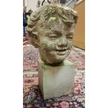 A carved white stone head of a young child, weathered,