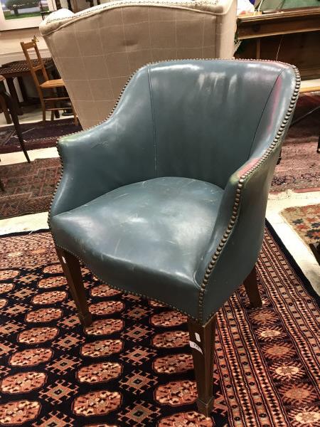 A circa 1900 blue leather upholstered tub chair raised on square tapered legs to spade feet