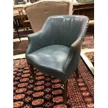 A circa 1900 blue leather upholstered tub chair raised on square tapered legs to spade feet
