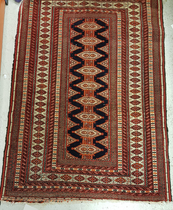 A Turkoman rug with repeating lozenge medallion decoration on a deep blue centre ground within a