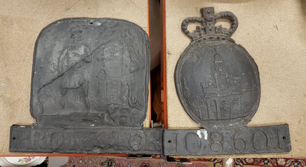 Two cast lead fire marks, one "protector" decorated with firemen and blazing house,