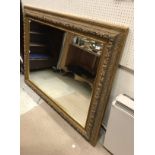 A large modern gilt framed wall mirror with scrolling foliate decoration