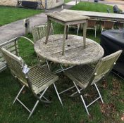 A teak garden table with three chairs and a stool