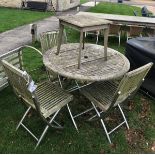 A teak garden table with three chairs and a stool