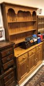 A modern stained pine dresser with three tier plate rack over three drawers and three cupboard