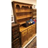 A modern stained pine dresser with three tier plate rack over three drawers and three cupboard