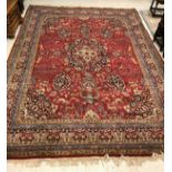 A Persian carpet with centre medallion on a red ground with all over decoration of exotic animals