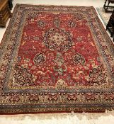A Persian carpet with centre medallion on a red ground with all over decoration of exotic animals