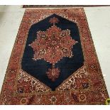 A Persian carpet with centre medallion on a blue ground within a red ground border,