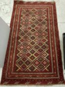 A Persian rug with all over lozenge medallion decoration on a red ground within a scrolling foliate