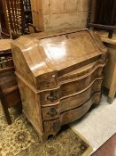 A Continental walnut and cross banded bureau with fall front over three serpentine drawers