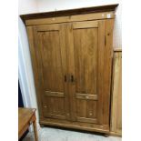 A Continental pine armoire with two cupboard doors enclosing a hanging space