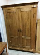 A Continental pine armoire with two cupboard doors enclosing a hanging space