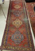 A Persian runner with repeating medallion decoration on a red ground approx.