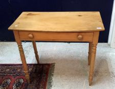 A pine single drawer side table with bow fronted top raised on turned legs
