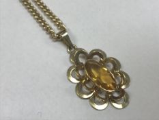 A nine carat gold and topaz set pendant of stylised flower form on a nine carat gold chain