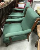 A pair of Victorian open arm chairs with green self patterned upholstery and oak frames raised on