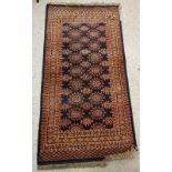 A Bokhara rug, the central panel set with repeating motifs on a dark blue ground,