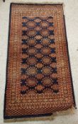 A Bokhara rug, the central panel set with repeating motifs on a dark blue ground,