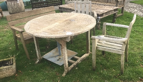 A teak garden table with two teak chairs and a bench