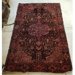 A Persian rug, the central panel set with floral decorated medallion on a dark blue and pink ground,