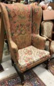 A 19th Century American upholstered wing back scroll arm chair on square supports united by