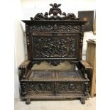 A carved painted and gilded walnut settle in the 17th Century Spanish taste the back with shield