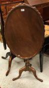 A 19th Century mahogany tea table the circular dished oval top with carved edge raised on a turned