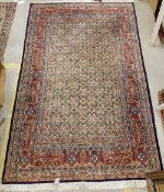 A Persian rug, the central panel set with all-over floral decoration on a cream ground,