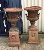 A pair of large terracotta urns on terracotta plinths CONDITION REPORTS One urn has