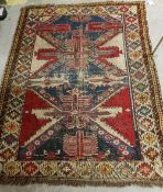 A Shirvan rug with a repeating medallion decoration on a red ground within a scrolling foliate