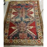 A Shirvan rug with a repeating medallion decoration on a red ground within a scrolling foliate