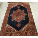 A Persian carpet with centre medallion on a blue ground within a red ground border,