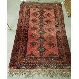 A Turkamen rug, the central panel set with repeating medallions on a red ground,